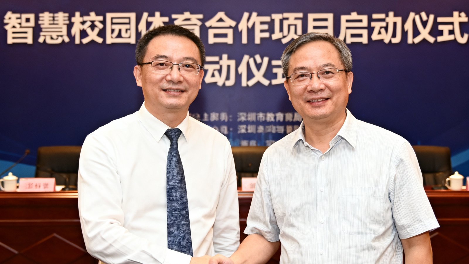 bwin必赢代表与深圳市教育局领导在签约仪式上握手合影，背景板上写着智慧校园体育合作项目启动仪式